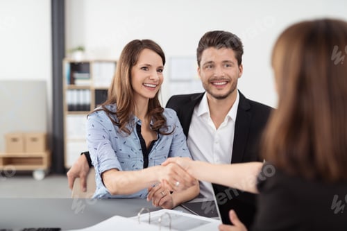 Preview: Happy Young Professional Couple Shaking Hands With A Real Estate Agent After Some Business