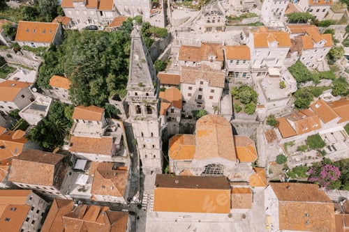Preview: Tall spire of the bell tower of the Church of St. Nicholas above the red roofs of the houses. Perast