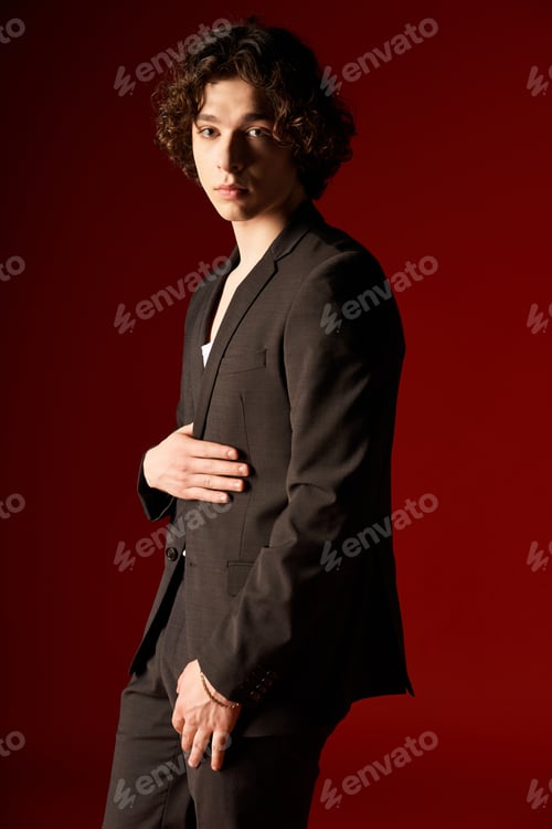 Preview: Stylish young man with curly hair poses confidently in a studio setting