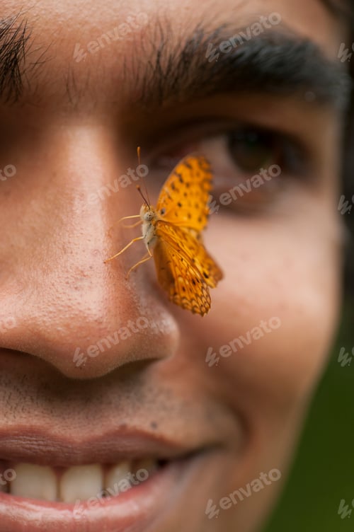 Preview: Butterfly sitting on a young man’s face, Symbiosis of man and nature.
