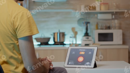 Preview: Man looking at tablet with intelligent software placed on kitchen table