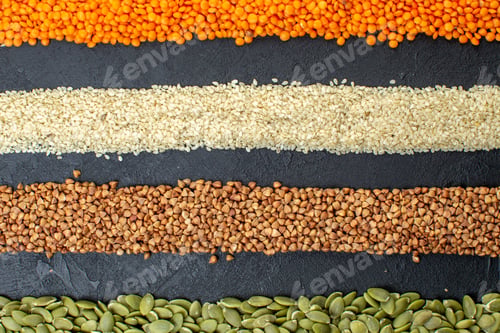 Preview: Top view of assorted grains of buckwheat pumpkin seeds corns rice on black background