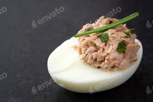 Preview: Boiled egg topped with tuna fish and chives on dark background