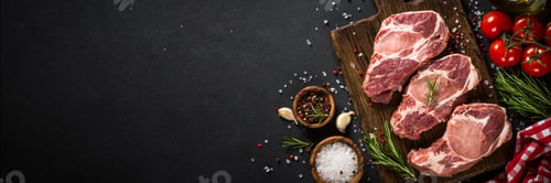 Preview: Pork meat at wooden board on black table