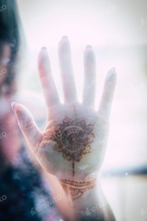 Preview: caucasian asiatic hand on a transparent glass with mandala painted