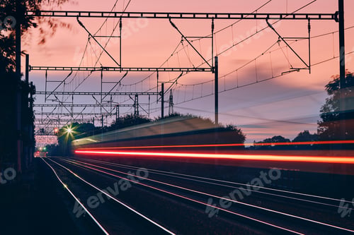 Preview: Railway at dawn. Light trails of passenger train on modern railroad track.