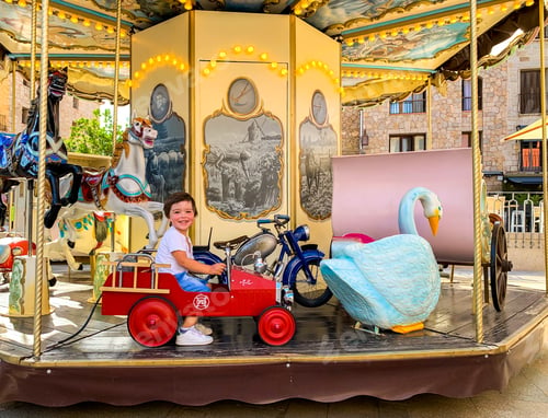 Preview: Happy little toddler boy enjoying riding merry go round alone during coronavirus pandemic