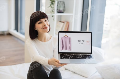 Preview: Woman Shows Clothing on Laptop in Bedroom Setting