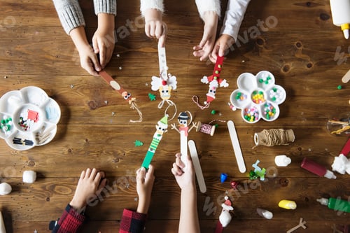 Preview: Kids hands holding Christmas character decorated popsicle sticks