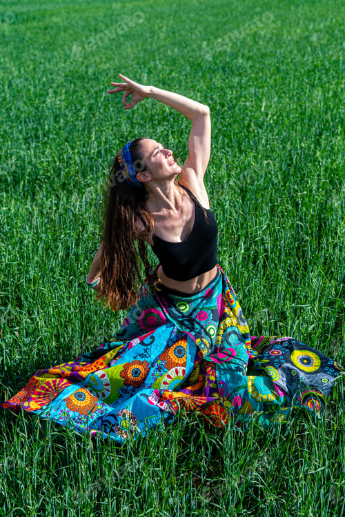 Preview: Young woman in a floral dress meditating in the grass field