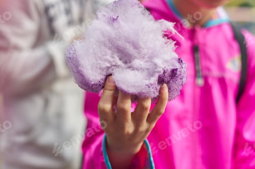 Preview: Girl child eating cotton candy floss, closeup sweet pink cloud