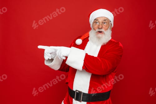 Preview: Santa Claus showing pointing fingers aside advertising Christmas promotion isolated red background