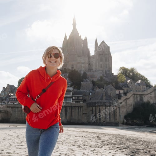 Preview: beautiful cheerful girl in red hoodie posing near Saint michaels mount, France