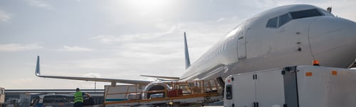 Preview: Worker loading baggage on conveyor belt to an airplane outdoors on a daytime