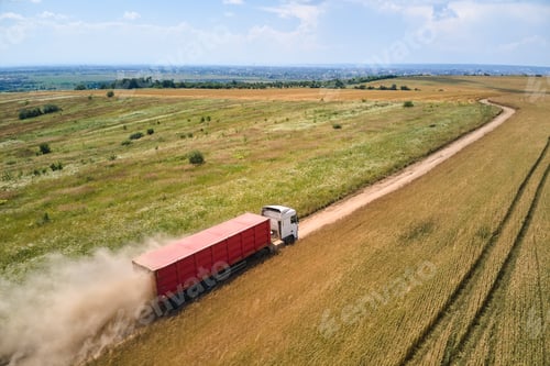 Preview: Aerial view of cargo truck driving on dirt road between agricultural wheat fields