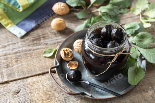 Preview: Handmade jam made from green fresh walnuts on a wooden background.