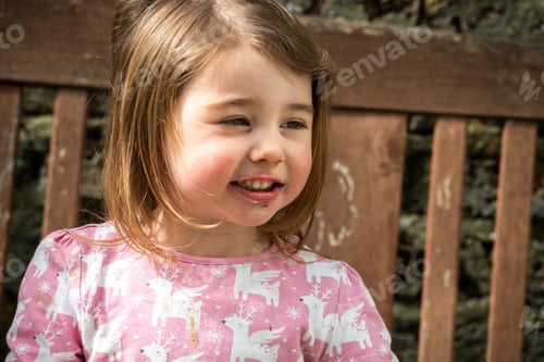 Preview: Little girl smiling outdoors on a sunny day