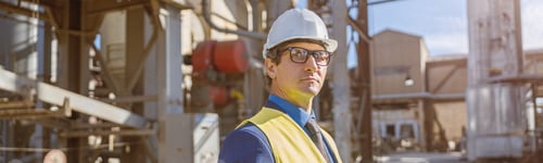 Preview: Male worker with laptop standing outdoors at factory