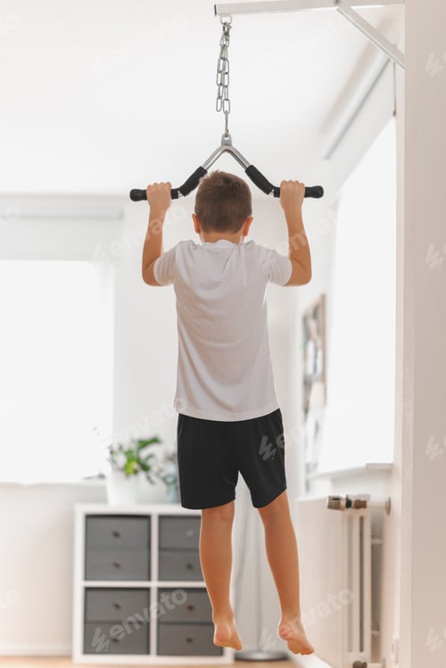 Preview: Young school boy doing pull-ups at home, stay fit. Active lifestyle, home workout