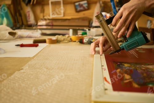 Preview: Man Framing Artwork Using Pneumatic Staple Gun