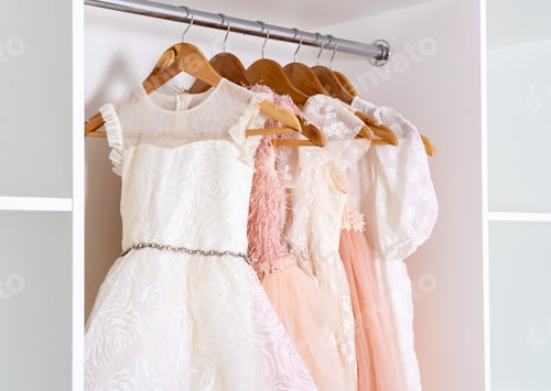 Preview: Dresses on hangers in white wardrobe.