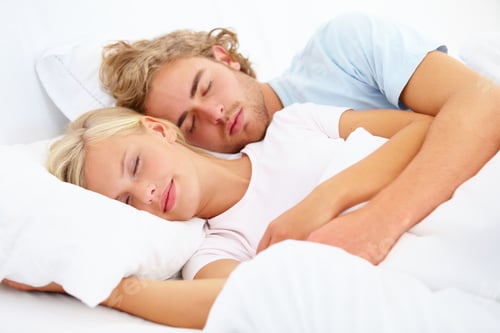 Preview: Asleep in his arms. A young couple fast asleep in bed together.