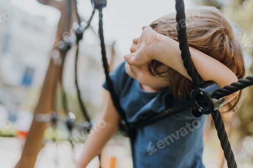 Preview: little brunette boy in a blue T-shirt is climbing a rope web. child is engaged in outdoor sports