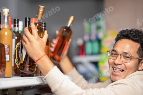 Preview: Man looking at camera while buying bottles of alcohol