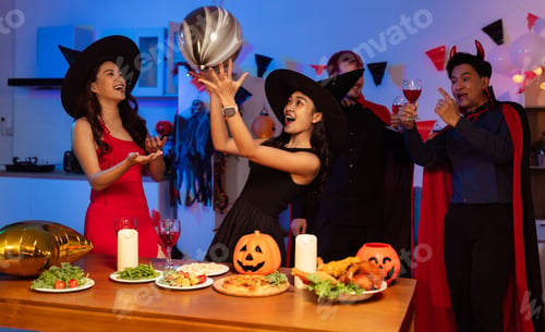 Preview: Dinner and group of people celebrating together at Halloween party.