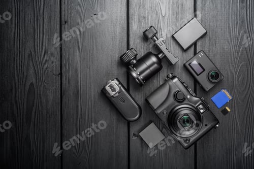 Preview: Digital compact and action cameras and equipment on black wooden plank table. top view.