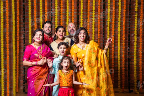 Preview: Indian family with grandparents and kids, excited and pointing in traditional Diwali attire