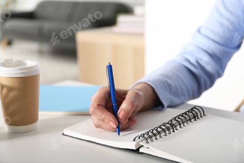 Preview: Woman taking notes at white table indoors, closeup. Self-study