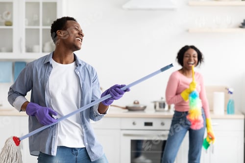 Preview: Playful black guy imitating rockstar while house-keeping