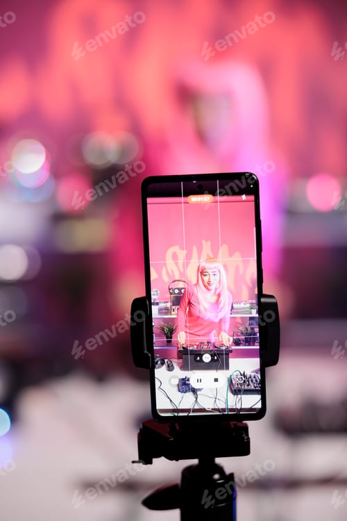 Preview: Cheerful artist with pink hair standing at dj table mixing song with turntables in front of camera