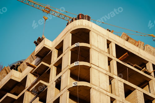 Preview: Construction site of a high-rise building under a clear blue sky with a crane in the background