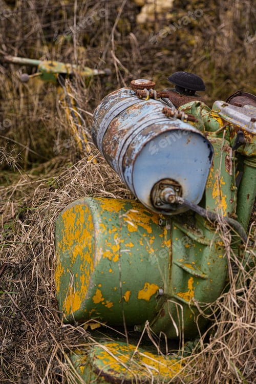 Preview: Vertical closeup shot of a rusty old broken industrial machine abandoned on a field