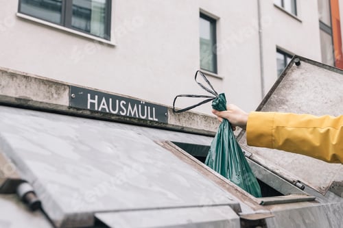 Preview: Person throwing garbage bag into dumpster outside a building