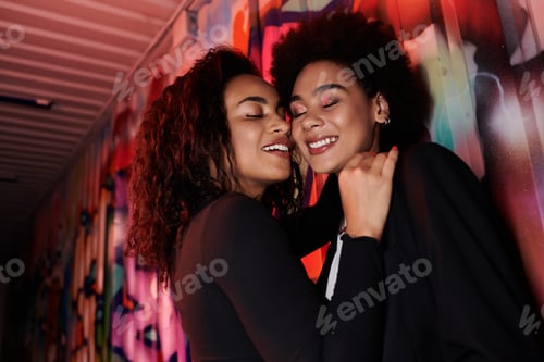 Preview: Warm embrace between two friends against vibrant street art in an urban setting