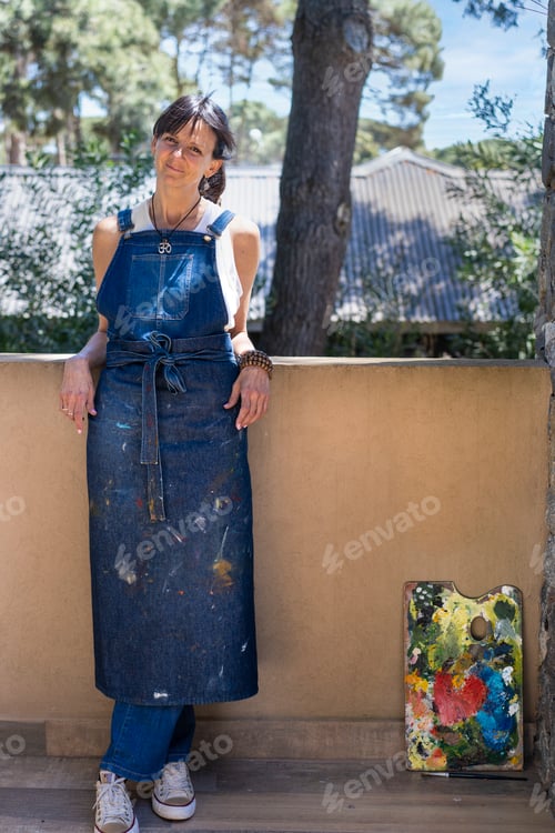 Preview: Portrait of a smiling woman artist looking at camera outdoors.
