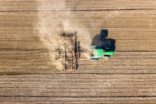Preview: Aerial view of a tractor plowing black agriculture farm field after harvesting in autumn.