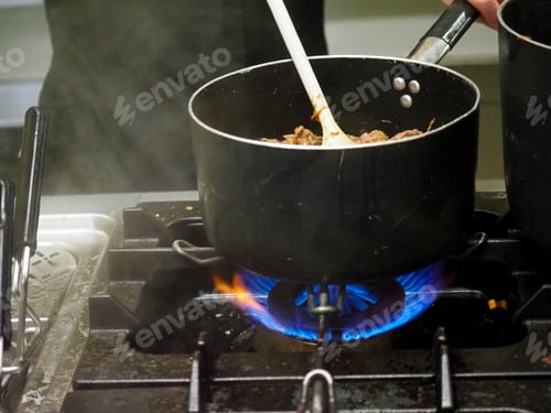 Preview: chef heating pulled meat in a pan in restaurant professional kitchen
