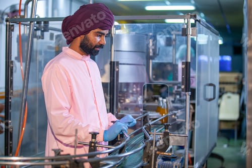 Preview: Asian man worker is checking product bottles of fruit juice on the production line.
