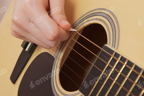Preview: Extreme closeup woman's fingers deftly handling guitar pick as strumming six string acoustic guitar