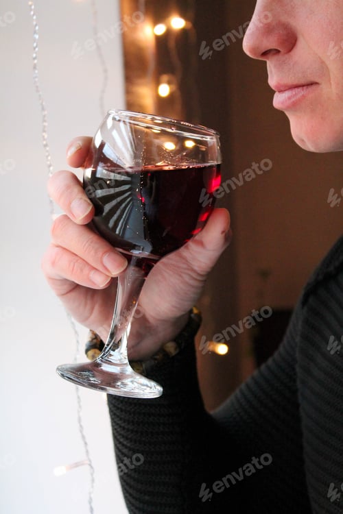 Preview: Young man in a black jumper drinks red wine from a glass.