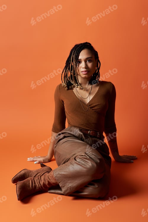 Preview: Stylish young Black woman with braids poses gracefully in a vibrant studio