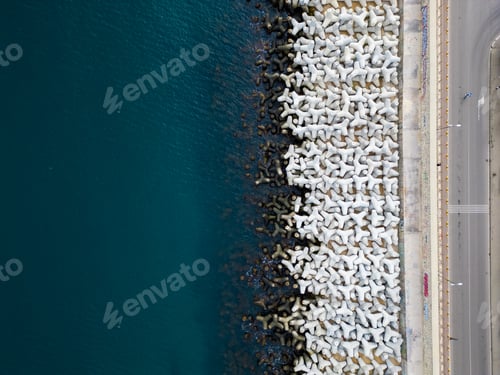 Preview: Heavy concrete tetrapods lined along the shoreline at a coastal area during daylight hours