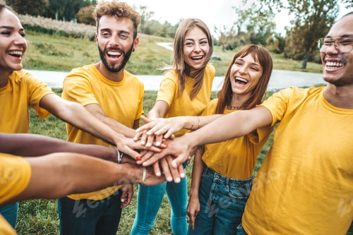 Preview: Multi ethnic young people team stacking hands together outside