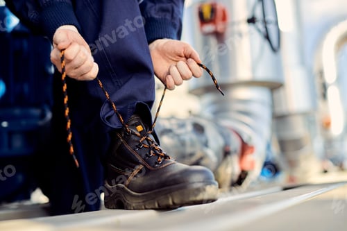 Preview: Unrecognizable manual worker typing shoelace at construction site.