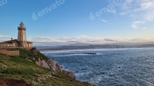 Preview: Distant view of the beautiful Faro de San Juan lighthouse at the coast in Asturias, Spain