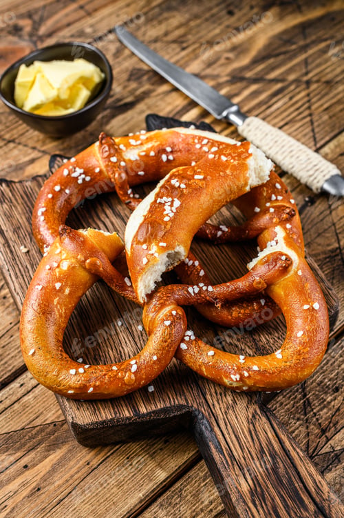 Preview: Baked pretzels with sea salt on a rustic wooden cutting board. Wooden background. Top view